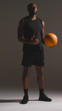 Vertical-Video-Full-Length-Studio-Shot-Of-Male-Basketball-Player-Throwing-Ball-From-One-Hand-To-The-Other-1